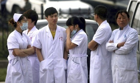 Medical staff wait near a poultry processing plant that was engulfed by a fire in northeast China's Jilin province's Mishazi township on Monday, June 3, 2013. 