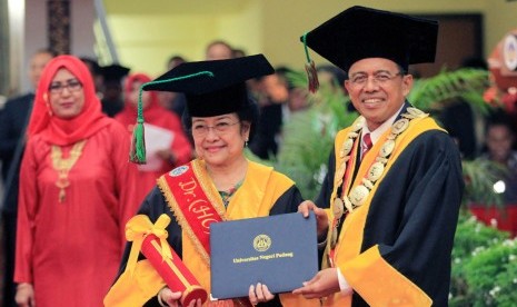 Megawati Soekarnoputri (tengah) menerima piagam Doktor yang diberikan Rektor Universitas Negeri Padang Ganefri (kanan) saat penganugerahan gelar Doktor Honoriis Causa Bidang Politik Pendidikan, di auditorium Universitas Negeri Padang (UNP), Sumatera Barat, Rabu (27/9). 