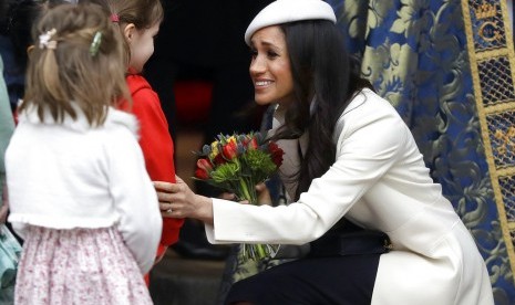 Meghan Markle menerima karangan bunga usai mengikuti Commonwealth Service di Westminster Abbey, Senin (12/3).