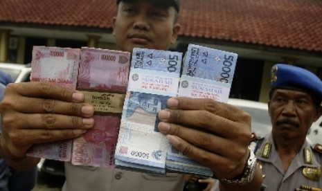 memperlihatkan barang bukti sejumlah uang palsu pecahan 100 ribuan.