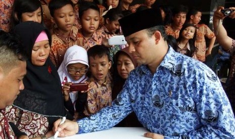  Menbuddikdasmen Anies Baswedan (kanan) disaksikan sejumlah pelajar SD ketika menuliskan kalimat penyemangat untuk para guru usai upacara peringatan Hari Guru Nasional di Kemenbuddikdasmen, Jakarta, Selasa (25/11). 