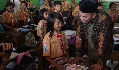 Mendikbud, Muhadjir Effendy (kanan) menanyai seorang siswa saat memantau penyaluran Kartu Indonesia Pintar (KIP) di SDN 1 Mangliawan 1, Malang, Jawa Timur, Jumat (2/9). 