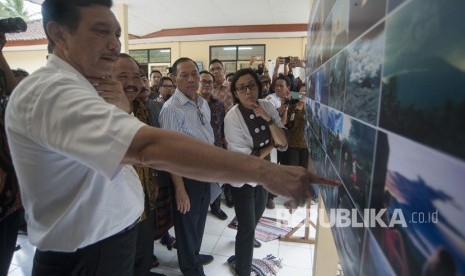 Menko Kemaritiman Luhut Binsar Pandjaitan (kiri) bersama Gubernur Bank Indonesia Agus Martowardojo (kedua kanan) dan Menteri Keuangan Sri Mulyani (kanan) melihat foto-foto erupsi Gunung Agung saat meninjau Pos Pengamatan Gunung Api Agung, di Desa Rendang, Karangasem, Bali, Jumat (22/12).