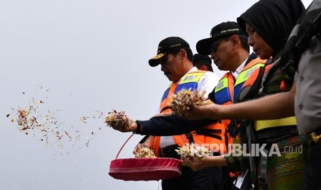 Menko Kemaritiman Luhut Binsar Pandjaitan (kiri) didampingi mantan Wakil Gubernur Sumut Nurhajizah Marpaung (kanan) dan Bupati Simalungun JR Saragih (tengah) menabur bunga untuk korban tenggelamnya KM Sinar Bangun di Danau Toba, Sumatra Utara, Senin (2/7).