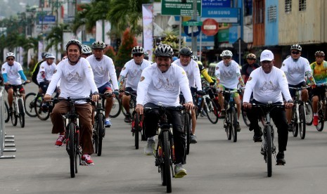 Menko Maritim Luhut B Panjaitan (kedua dari kiri) didampingi Gubernur Maluku Said Assagaff (kiri) bersepeda mengelilingi sejumlah ruas jalan di Kota Ambon usai membuka lomba balap sepeda internasional Tour de Moluccas 2017 di Ambon, Maluku, Minggu (17/8). 