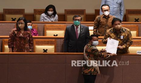 Menko Perekonomian Airlangga Hartarto (kanan) didampingi Menkumham Yasonna Laoly (kedua kiri) dan Menteri Keuangan Sri Mulyani (kiri) menerima laporan akhir dari Ketua Badan Legislasi DPR Supratman Andi (bawah) saat pembahasan tingkat II RUU Cipta Kerja pada Rapat Paripurna DPR di Kompleks Parlemen, Jakarta, Senin (5/10/2020).