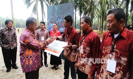 Menko Perekonomian Darmin Nasution (kedua kiri) disaksikkan Menteri ATR/Kepala BPN Sofyan Djalil (kiri) menyerahkan secara simbolis dana Kredit Usaha Rakyat (KUR) kepada pengurus koperasi saat peresmian Program Peremajaan Kebun Sawit Rakyat di Desa Pelita, Kecamatan Bagan Sinembah, Rokan Hilir, Riau, Rabu (9/5).