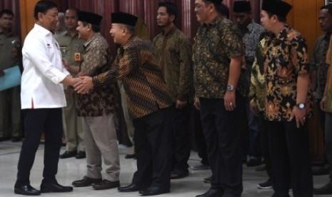 Menko Polhukam Wiranto (kiri) berjabat tangan dengan anak pemimpin Darul Islam/Tentara Islam Indonesia (DI/TII) Sekarmaji Marijan Kartosuwiryo, Sarjono Kartosuwiryo (tengah) dalam acara pengucapan ikrar setia kepada Pancasila, UUD 45, NKRI dan Bhineka Tunggal Ika di Jakarta, Selasa (13/08/2019). 