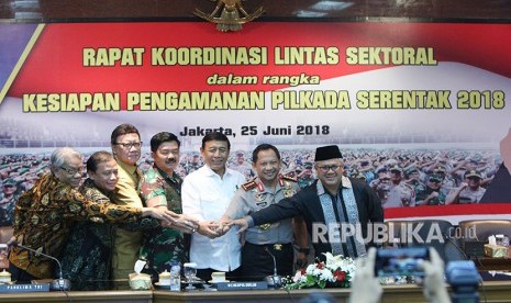 Menkopolhukam Wiranto (ketiga kanani) bersama Kapolri Jenderal Pol Tito Karnavian (kedua kanan), Ketua KPU Arief Budiman (kanan), Panglima TNI Marsekal TNI Hadi Tjahjanto (keempat kirii), Menteri Dalam Negeri Tjahjo Kumolo (ketiga kiri), Ketua Bawaslu Abhan (kedua kiri), dan ketua Dewan Kehormatan Penyelenggara Pemilu Harjono (kiri) bertumpu tangan bersama seusai Rapat koordinasi lintas sektoral kesiapan pengamanan Pilkada serentak di ruang Rupatama Mabes Polri, Jakarta, Senin (25/6). 