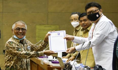 Menpan RB Tjahjo Kumolo (kanan) menerima pandangan fraksi dari Anggota DPR fraksi PAN Guspardi Gaus (kiri) saat mengikuti rapat pleno bersama Badan Legislasi DPR di Kompleks Parlemen, Senayan, Jakarta, Senin (22/11/2021). Rapat pleno tersebut untuk mengambil keputusan atas hasil pembahasan RUU tentang pembentukan pengadilan tinggi, pengadilan tinggi agama, dan pengadilan tinggi tata usaha negara di sejumlah daerah salah satunya adalah Papua Barat, Kepulauan Riau, dan Palembang.