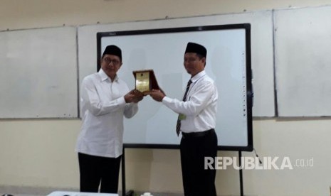 Menteri Agama Lukman Hakim Saifuddin menerima plakat dari Kepala MAN 4 Jakarta Ismail Nur usai meninjau UNBK di MAN 4 Jakarta, Selasa (11/4). 