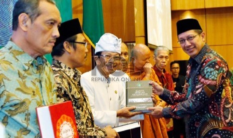 Menteri Agama RI Lukman Hakim Saifudin (kanan) secara simbolis menyerahkan Alquran dengan terjemahan bahasa daerah kepada beberapa perwakilan tokoh lintas agama dan tokoh daerah pada peluncurannya, Kamis (3/12), di Jakarta. 