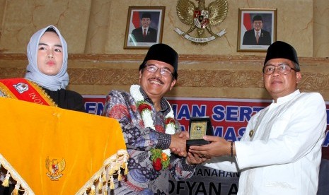 Menteri Agraria dan Tata Ruang/Kepala Badan Pertanahan Nasional Sofyan Djalil (tengah) memberikan cenderamata kepada Bupati Aceh Barat Ramli Ms (kanan) seusai menyerahkan sertifikat tanah wakaf di Aula Kantor Bupati Aceh Barat, Aceh, Jumat (15/2/2019). 