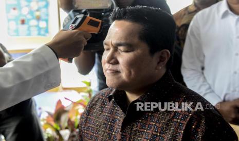 Menteri BUMN Erick Thohir diukur suhu tubuhnya saat meninjau salah satu gerai apotek Kimia Farma di kawasan Cikini, Jakarta, Rabu (4/3).