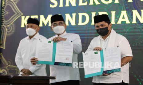 Menteri BUMN Erick Thohir (kanan) bersama Ketua Umum Pengurus Besar Nahdlatul Ulama (PBNU) KH Yahya Cholil Staquf (kedua kanan) menunjukkan dokumen nota kesepahaman antara Kementerian BUMN dengan PBNU terkait pengembanganan wirausaha di lingkungan NU dan lingkungan santri saat puncak peringatan Hari Lahir (Harlah) ke-99 NU di Bangkalan, Madura, Jawa Timur, Kamis (17/2/2022). Harlah ke-99 NU itu mengusung tema Menyongsong 100 Tahun NU Merawat Jagat Membangun Peradaban. 