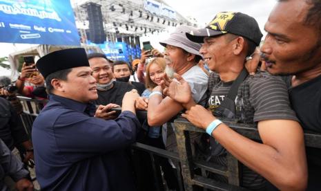 Menteri BUMN Erick Thohir (kiri) berbincang dengan warga saat menghadiri konser Salam Satu Jiwa di Bekasi, Jawa Barat, Ahad (8/1/2023). Konser Salam Satu Jiwa tersebut merupakan bentuk dukungan dan solidaritas terhadap korban tragedi Kanjuruhan di Malang.