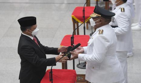 Menteri Dalam Negeri Tito Karnavian (kiri) menyerahkan surat keputusan kepada Pj. Gubernur Papua Barat Paulus Waterpauw (kanan) saat pelantikan lima penjabat gubernur di Kemendagri, Jakarta, Kamis (12/5/2022).