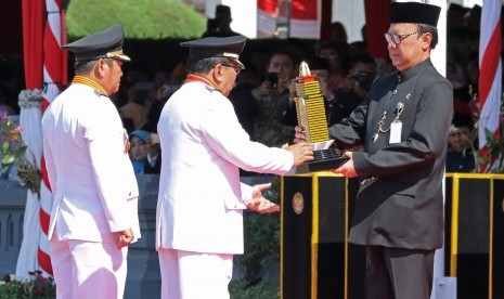 Menteri Dalam Negeri Tjahjo Kumolo (kanan) menyerahkan penghargaan Samkarya Parasamya Purnakarya Nugraha kepada Gubernur Jawa Timur Soekarwo (kedua kanan) saat Upacara Hari Jadi Ke-72 Provinsi Jawa Timur di Tugu Pahlawan, Surabaya, Jawa Timur, Kamis (12/10). 