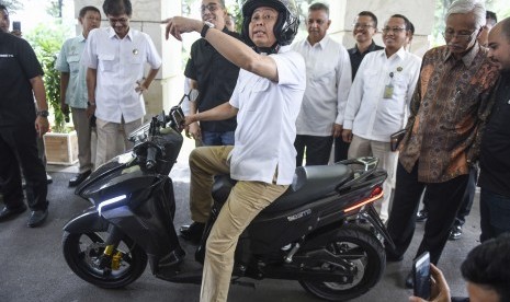 Menteri ESDM Ignasius Jonan (tengah) disaksikan Direktur Utama PLN Sofyan Basir (kelima kanan), Dirjen EBTKE Kementerian ESDM Rida Mulyana (kiri) dan CEO Garasindo Group Muhammad Al Abdullah (kedua kiri) mencoba motor listrik Gesits (Garasindo Electric Scooter ITS) di Kementerian ESDM, Jakarta, Kamis (19/10).