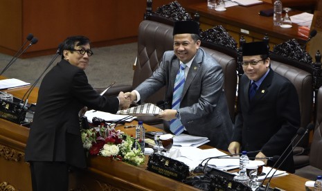 Menteri Hukum dan HAM Yasonna Laoly (kiri) menyerahkan salinan pandangan akhir pemerintah kepada pimpinan rapat paripurna Fahri Hamzah (tengah) dan Taufik Kurniawan (kanan) terkait RUU Jasa Konstruksi di Kompleks Parlemen Senayan, Jakarta, Kamis (15/12). 