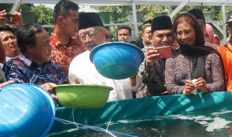 Menteri Kelautan dan Perikanan Susi Pudjiastuti (kanan) dan Pengasuh Ponpes Tebuireng KH Salahuddin Wahid (tengah) menebar benih ikan lele sistem bioflok di SMA Trensains Tebuireng di Desa Jombok, Ngoro, Jombang, Jawa Timur, Ahad (13/8). 