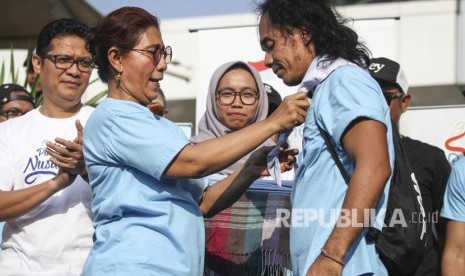 Menteri Kelautan dan Perikanan Susi Pudjiastuti menyematkan syal kepada musisi grup band Slank Kaka (kanan) saat meresmikan Pandu Laut Nusantara di kawasan Bundaran HI, Jakarta, Minggu (15/7). 