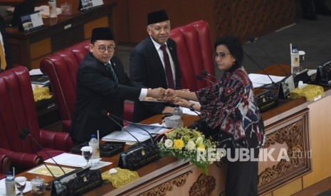 Menteri Keuangan Sri Mulyani Indrawati (kanan) memberikan draft tanggapan pemerintah kepada Ketua Rapat Paripurna Fadli Zon (kiri) didampingi Wakil Ketua DPR Agus Hermanto (tengah) pada Rapat Paripurna DPR di Kompleks Parlemen, Senayan, Jakarta, Selasa (11/6/2019).