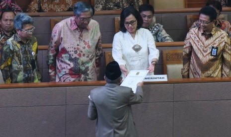 Menteri Keuangan Sri Mulyani (kedua kanan) didampingi Wakil Menteri Keuangan Mardiasmo (kedua kiri) menerima pandangan fraksi atas pertanggungjawaban pelaksanaan APBN 2017 dari anggota DPR fraksi PKS Refrizal (tengah) saat Rapat Paripurna di Kompleks Parlemen Senayan, Jakarta, Selasa (10/7).