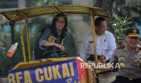 Menteri Keuangan Sri Mulyani (kiri) melempar minuman keras bersama Kapolda Metro Jaya M. Iriawan (kanan) dan Kepala BNN Budi Waseso (tengah) saat pemusnahan barang ilegal hasil sitaan bea cukai di halaman gedung Bea Cukai, Jakarta Timur, Jumat (23/12).