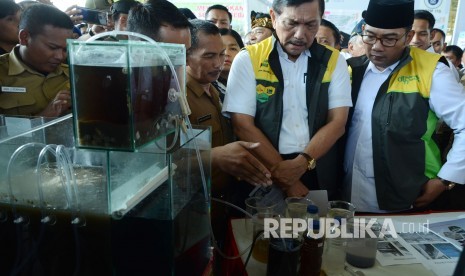 Menteri Koordinator Bidang Kemaritiman, Luhut Binsar Panjaitan di dampingi Gubernur Jawa Barat Ridwan Kamil mengamati alat penyaring air saat meninjau pameran Citarum Expo 2019, di Gedung Budaya Sabilulungan, Kabupaten Bandung, Selasa (19/2).