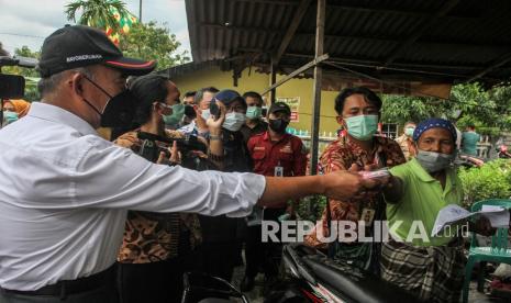 Menteri Koordinator Bidang Pembangunan Manusia dan Kebudayaan Muhadjir Effendy membagikan masker kepada warga saat melakukan kunjungan kerja ke Pekanbaru, Riau, Selasa (8/2/2022). Menko PMK meninjau langsung program penerimaan Bantuan Sosial sekaligus membagikan langsung paket bantuan 