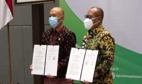 Menteri Koperasi dan UKM Teten Masduki (kiri) dan Dirut BP JAMSOSTEK Agus Susanto (kanan) saat menunjukkan akta penandatanganan nota kesepahaman kerja sama antara BP JAMSOSTEK dan Kementerian UKM dan Koperasi di Plaza BP JAMSOSTEK, Jakarta, Rabu (4/11). 