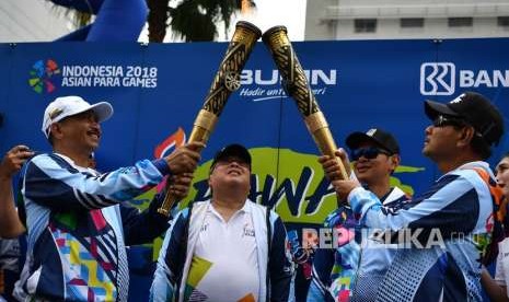 Menteri Pariwisata Arief Yahya (kiri) menyalurkan api dari Obor Asian Para Games 2018 kepada Direktur Utama Bank BRI Suprajarto (kanan) disaksikan Menteri PPN/Kepala Bappenas Bambang Brodjonegoro (kedua kiri) dan Ketua Umum INAPGOC Raja Sapta Oktohari (kedua kanan) dalam perhelatan Parade Pawai Obor Asian Para Games 2018 di Jalan MH Thamrin, Jakarta, Ahad (30/9).