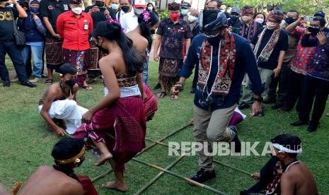 Menteri Pariwisata dan Ekonomi Kreatif (Menparekraf) Sandiaga Salahuddin Uno (kanan) mencoba permainan tradisional saat mengunjungi Desa Wisata Tenganan Pegringsingan, Karangasem, Bali, Jumat (24/9/2021). Kunjungan tersebut dilakukan Sandiaga Uno dalam rangkaian Anugerah Desa Wisata Indonesia (ADWI) 2021 untuk mendorong desa wisata menjadi destinasi pariwisata berkelas dunia, berdaya saing dan berkelanjutan serta menjadi salah satu alternatif destinasi wisata yang aman pada masa pandemi COVID-19. 