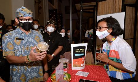 Menteri Pariwisata dan Ekonomi Kreatif (Menparekraf) Sandiaga Salahuddin Uno (kiri) mengamati produk industri kreatif yang dijual pada Pameran Apresiasi Kreasi Indonesia 2021 di kawasan Seminyak, Badung, Bali, Sabtu (25/9/2021). Apresiasi Kreasi Indonesia 2021 yang diselenggarakan Kemenparekraf di 16 deerah di Indonesia merupakan program pengembangan ekonomi kreatif melalui peningkatan kapasitas dan pameran kepada para pelaku ekonomi kreatif pada subsektor kuliner, kriya, fesyen, musik, film, animasi, aplikasi dan permainan.