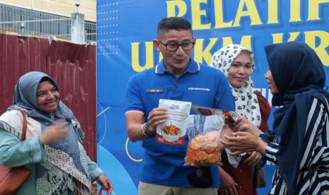 Menteri Pariwisata dan Ekonomi Kreatif (Menparekraf) Sandiaga Salahuddin Uno (tengah) menerima produk UMKM yang telah dikemas seusai memberikan materi pelatihan UMKM kreatif kepada pelaku usaha kecil di Banda Aceh, Aceh, Rabu (3/8/2022).