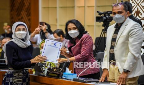 Menteri Pemberdayaan Perempuan dan Perlindungan Anak I Gusti Ayu Bintang Darmawati Puspayoga (tengah) bersama Wakil Menteri Hukum dan HAM Edward Omar Sharif Hiariej (kanan) menerima laporan mini fraksi dari Anggota Baleg fraksi PAN Desy Ratnasari (kiri) saat mengikuti Rapat Pleno pengambilan keputusan atas hasil pembahasan RUU tentang Tindak Pidana Kekerasan Seksual dengan Badan Legislasi DPR di Kompleks Parlemen, Senayan, Jakarta, Rabu (6/4/2022). Dalam Rapat pleno tersebut Badan Legislasi DPR menyetujui Rancangan Undang-Undang Tindak Pidana Kekerasan Seksual (RUU TPKS) untuk segera disahkan jadi undang-undang dalam Rapat Paripurna