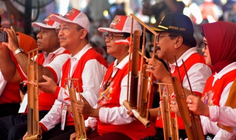 Menteri Pemberdayaan Perempuan dan Perlindungan Anak Yohana Susana Yembise (tengah) Gubernur Jawa Timur Soekarwo (kedua kanan) memainkan alat musik angklung saat puncak peringatan Hari Anak Nasional 2018 di Kebun Raya Purwodadi, Pasuruan, Jawa Timur, Senin (23/7).