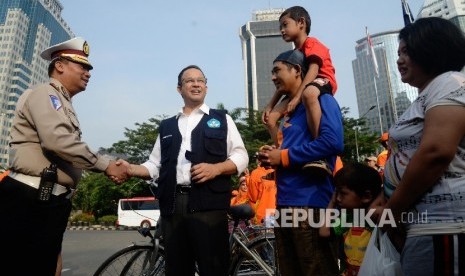 Menteri Pendidikan dan Kebudayaan Anies Baswedan berbincang dengan pengunjung car free day saat sosialisasi kampanye anter anak pada hari pertama sekolah di Patung Kuda, Jakarta, Ahad (17/7). (Republika/Yasin Habibi) 