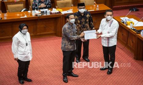 Menteri Pendidikan dan Kebudayaan Nadiem Makarim (kedua kiri) didampingi Menteri Sosial Tri Rismaharini (kiri) menyerahkan Daftar Inventarisasi Masalah (DIM) RUU tentang Praktik Psikologi kepada Ketua Komisi X DPR Syaiful Huda (kanan) dalam rapat kerja di Kompleks Parlemen, Senayan, Jakarta, Senin (22/3/2021). Rapat tersebut membahas terkait penjelasan Ketua Komisi X DPR dan pandangan pemerintah terhadap RUU tentang Praktik Psikologi. 