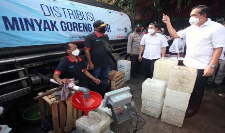 Menteri Perdagangan Muhammad Lutfi (kanan) berbincang dengan pekerja saat meninjau langsung pendistribusian minyak goreng curah untuk pedagang eceran di Pasar Kebayoran Lama, Jakarta, Rabu (9/3/2022).