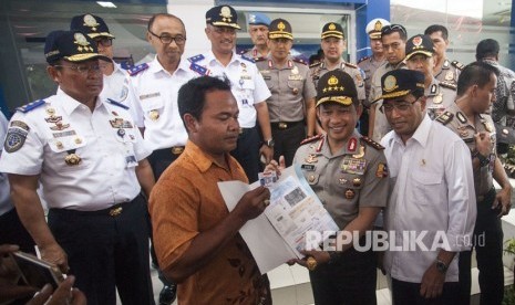 Menteri Perhubungan Budi Karya Sumadi (kanan) dan Kapolri Tito Karnavian (kedua kanan) menyerahkan SIM kepada driver online saat meninjau pembuatan SIM A untuk driver atau pengemudi taksi online di Polresta Yogyakarta, DI Yogyakarta, Ahad (10/3).