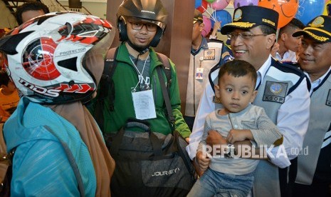 Menteri Perhubungan Budi Karya Sumadi (kedua kanan) menggendong seorang anak sambil berbicang dengan pemudik gratis bersepeda motor asal Jakarta yang baru turun dari KM Sabuk Nusantara 80, di Pelabuhan Tanjung Emas, Semarang, Jawa Tengah, Rabu (13/6). 