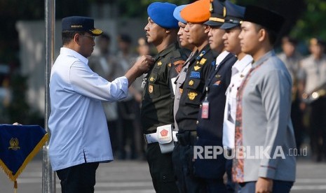 Menteri Perhubungan Budi Karya Sumadi (kiri) menyematkan pin kepada anggota TNI saat apel gelar pasukan Angkutan Lebaran 2019 di Stasiun Gambir, Jakarta Pusat, Ahad (26/5/2019).