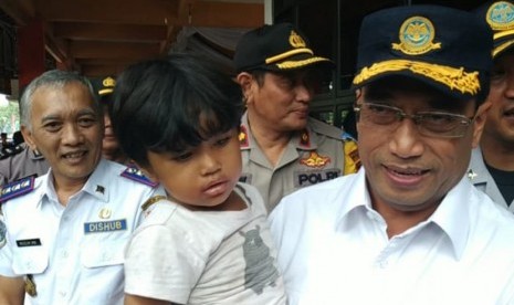 Menteri Perhubungan Budi Karya Sumadi menggendong salah seorang anak pemudik saat melakukan peninjauan di Terminal Kampung Rambutan, Jakarta Timur, Kamis (6/6).