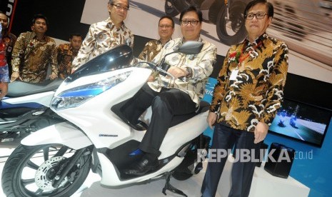 Menteri Perindustrian Airlangga Hartarto (kedua kanan) mencoba Honda PCX Electric disaksikan Presiden Direktur PT Astra Honda Motor Toshiyuki Inuma (keempat kanan), Marketing Director Thomas Wijaya (ketiga kanan) dan Ketua Umum Asosiasi Industri Sepedamotor Indonesia Johannes Loman (kanan), di stan Honda pada pembukaan Indonesia Motorcycle Show (IMOS) 2018 di Jakarta, Kamis (31/10/2018).