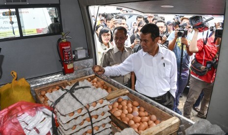 Menteri Pertanian Amran Sulaiman (kanan) didampingi Kepala Badan Ketahanan Pangan Agung Hendriadi (kedua kiri) memeriksa telur ayam yang akan didistribusikan untuk operasi pasar di Toko Tani Indonesia Centre, Jakarta Selatan, Kamis (19/7).