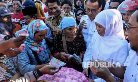 Menteri Pertanian, Andi Amran Sulaiman (ketiga kiri) menyaksikan Gubernur Jatim Khofifah Indar Parawansa (kedua kanan) melayani warga membeli bawang putih saat operasi pasar murah bawang putih di pasar baru porong, Sidoarjo, Jawa Timur, Rabu (22/5/2019). 