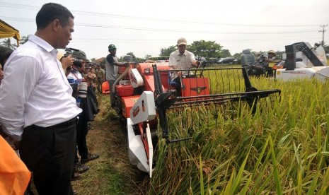 Menteri Pertanian Andi Amran Sulaiman memperhatikan proses panen padi menggunakan mesin Combine Harvester saat panen raya di Desa Babadan, Tegal, Jawa Tengah, Kamis (31/3). 