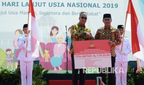 Menteri Sosial Agus Gumiwang Kartasasmita (kiri) secara simbolis menyerahkan bantuan Kepada Gubernur Jawa Barat Ridwan Kamil pada Puncak Hari Lansia Nasional 2019, di Monumen perjuangan Rakyat Jawa Barat (Monju), Kota Bandung, Rabu (10/7). 